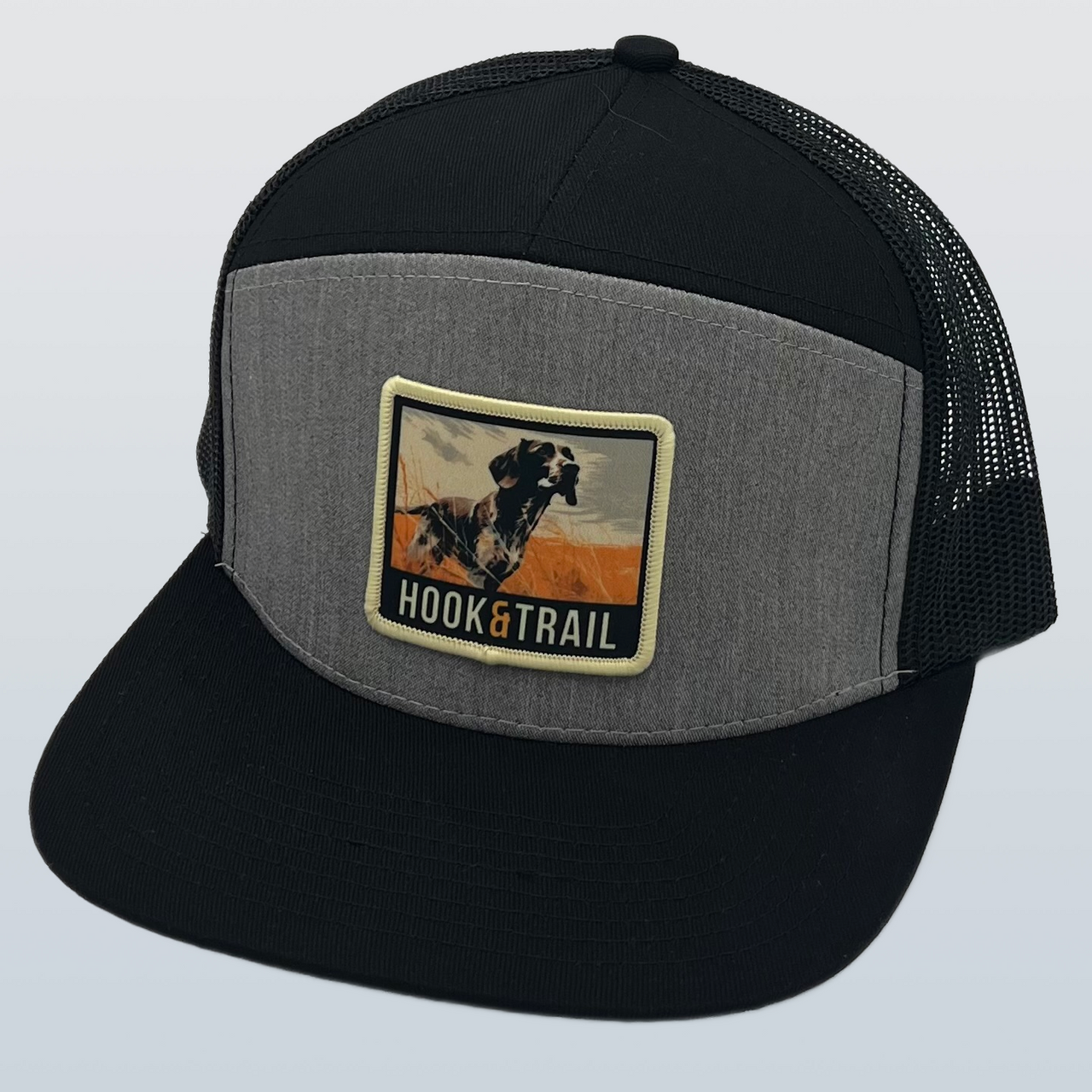 Heather Grey/Black 7 Panel Cap by Hook & Trail with Pointer Patch emblem. Modern design, durable construction, and adjustable strap for comfort. Versatile and stylish accessory for outdoor adventures and urban exploration.