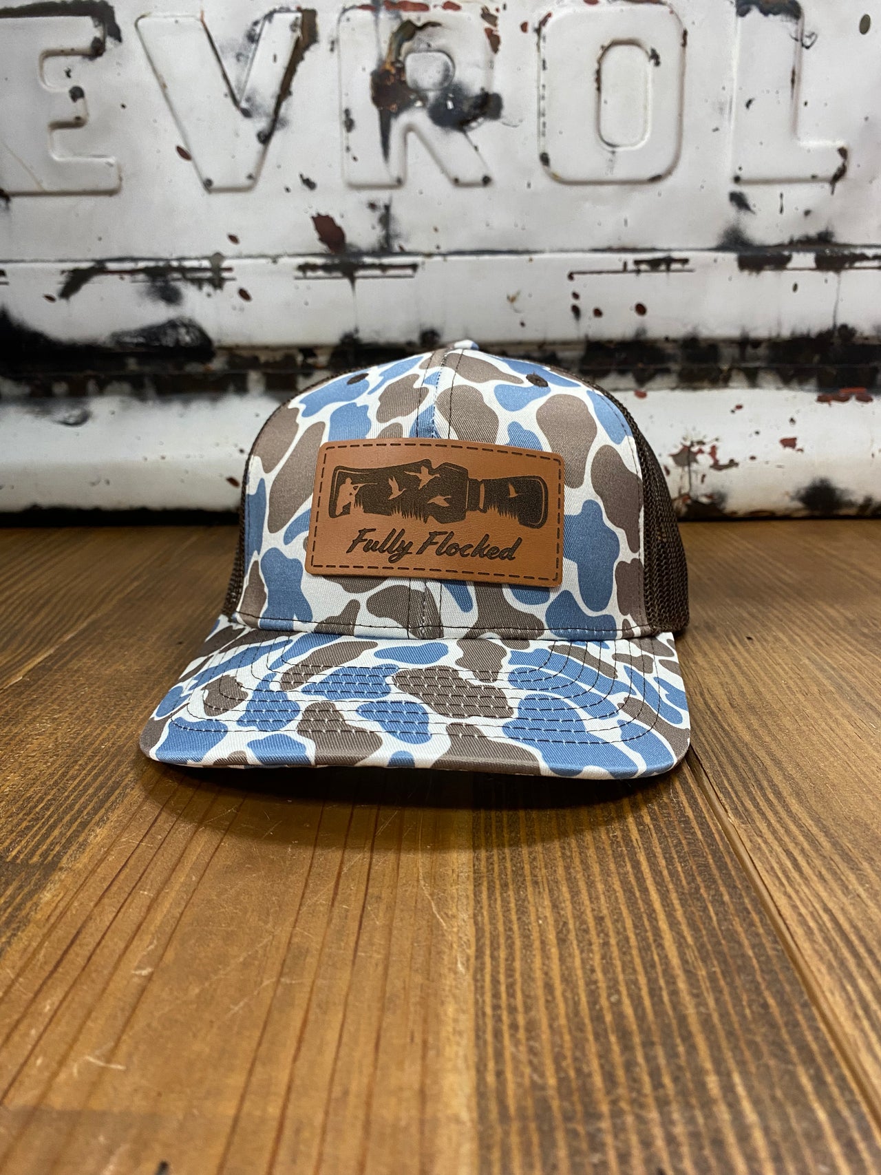 Fully Flocked Blue Old School Camo Snapback Hat featuring a richardson 112 trucker cap style, adorned with a leather patch showcasing elegant flying mallards. The blue old school camo print and brown mesh snapback create a perfect blend of classic and contemporary outdoor fashion.