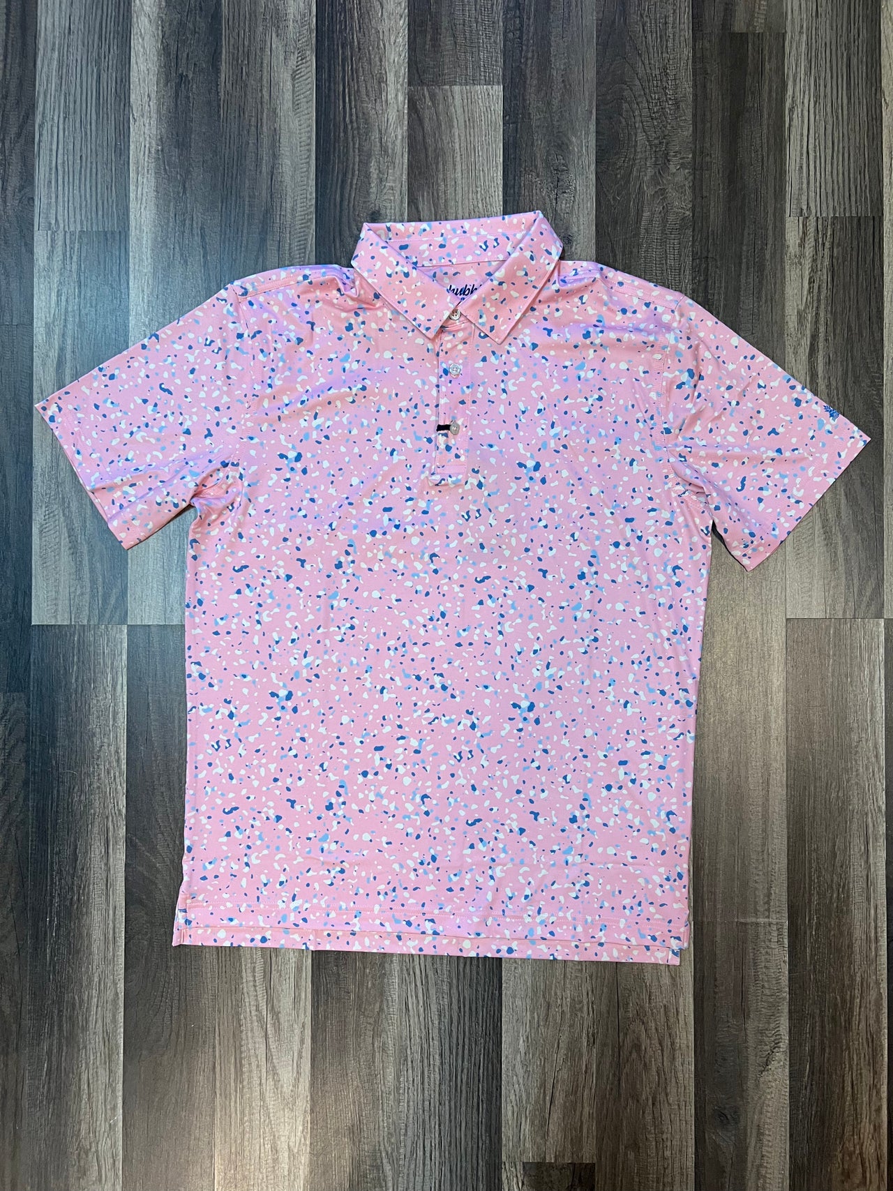  "Chubbies Performance Polo - The Funfetti in Pink with Blue Confetti: A vibrant and energetic polo shirt featuring a playful blend of pink and blue confetti patterns. Crafted from moisture-wicking fabric for ultimate comfort and performance. Perfect for any activity, this tailored-fit polo combines style and functionality with a three-button placket and ribbed collar."