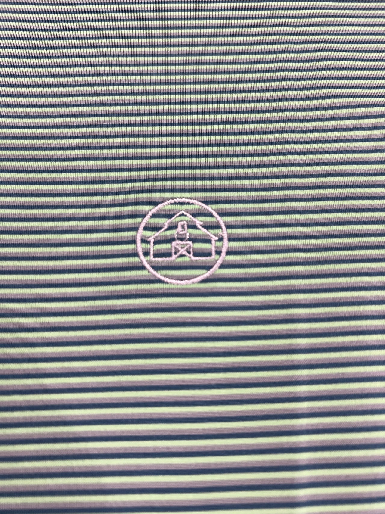 A close-up image of a lime, silver, and teal striped polo shirt from Home Bound Brand, showcasing its vibrant colors and modern design.